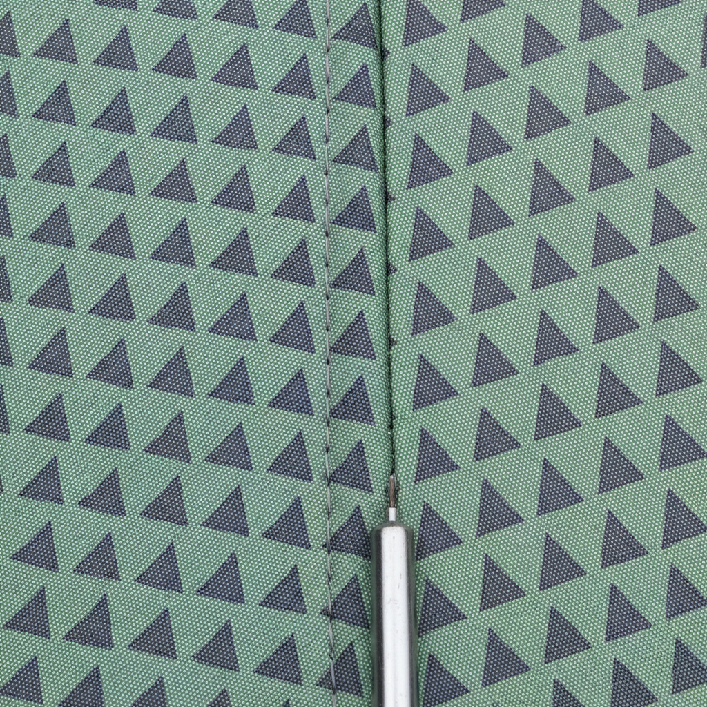 Macro on a canopy seam, where the same sage and charcoal triangle repeat comes out visibly larger and sitting at different heights on the right of the stitching than on the left, so the rows break at the seam instead of carrying across it